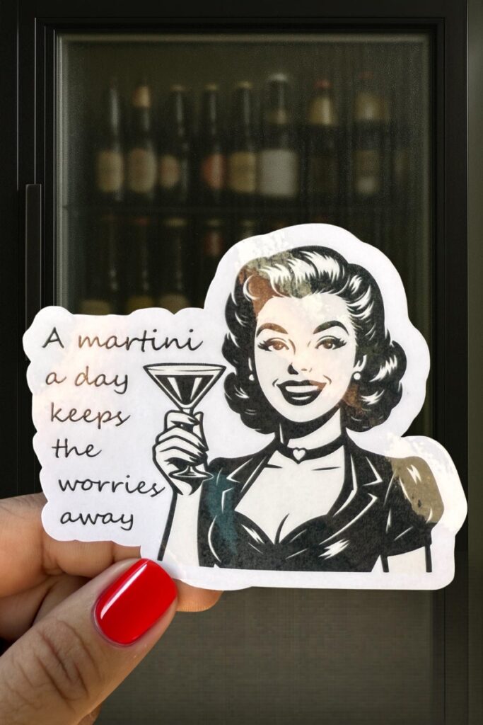 Retro-style sticker of a glamorous woman holding a martini glass, with the phrase “A martini a day keeps the worries away.”