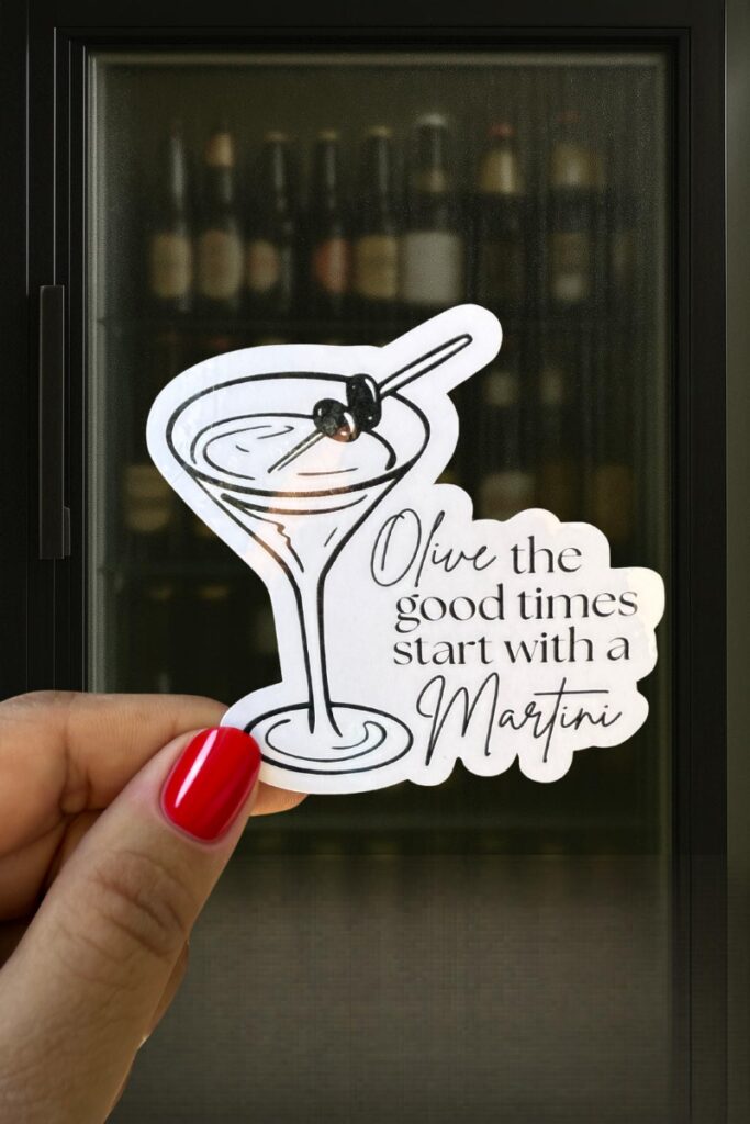 Sticker of a martini glass with two olives on a toothpick, captioned “Olive the good times start with a Martini.”