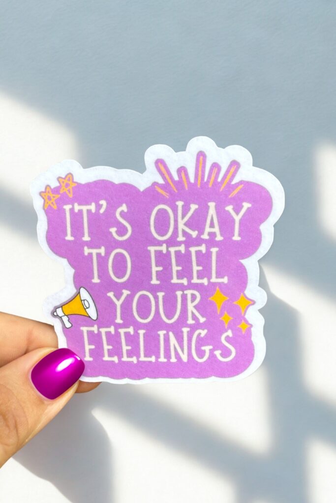 Purple sticker with white text reading “It’s Okay to Feel Your Feelings,” decorated with stars, sparkles, and a small megaphone—celebrating emotional honesty and mental health awareness.